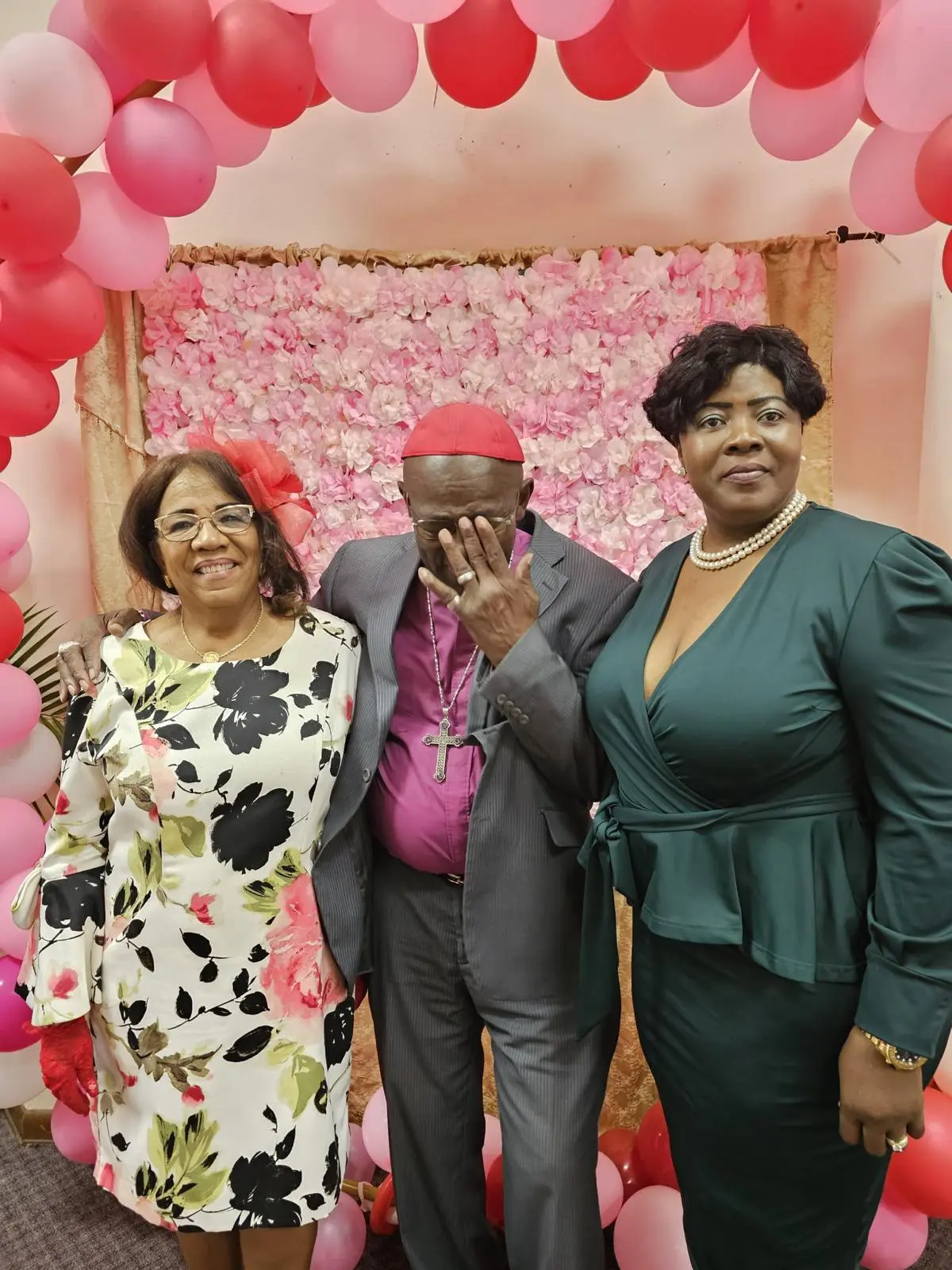 Three people together at a celebration decorated with balloons