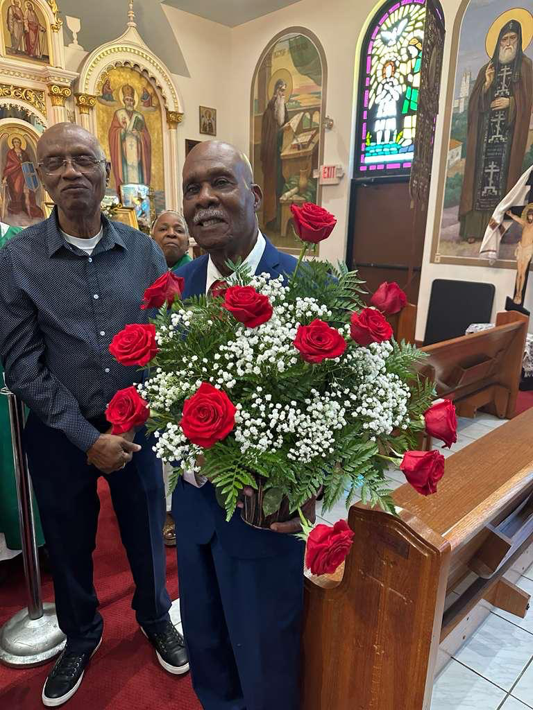 People posing together with a bouquet of red roses inside the church